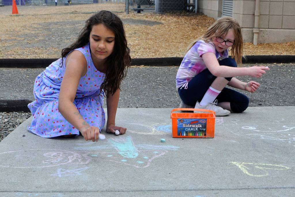 Sequim Gazette photo by Matthew Nash/ Fourth graders Nevaeda Steele and Abigail McBride add to the sidewalk chalk art display on June 11 at Helen Hallers Field Day. The girls said they were having a lot of fun during the annual event.
