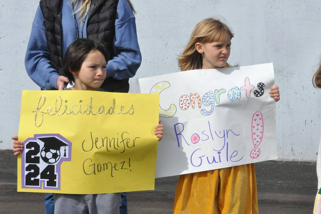 Sequim Gazette photo by Matthew Nash/ First graders Caden Reyes and Hazel Griffith await Sequim High seniors coming around for high-fives and hellos during the SHS Grad Walk.