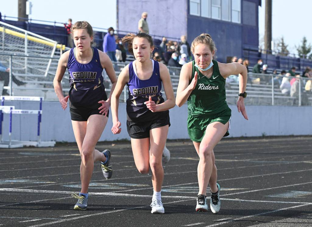 Sequim Gazette file photo by Michael Dashiell / From left, Sequims Anastasia Updike and Mikiah Winter and Port Angeles Lauren Larson break from the starting line in the 1,600-meter race at an Olympic League track and field meet in Sequim on March 31, 2021. The meet wound up being the last the Wolves hosted for more than three years after the surface was deemed unsuitable for competition.