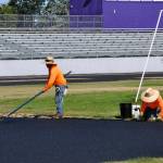 Sequim Gazette photo by Matthew Nash
Workers with Beynon Sports of Oregon flatten new material for the high jump area on July 19.