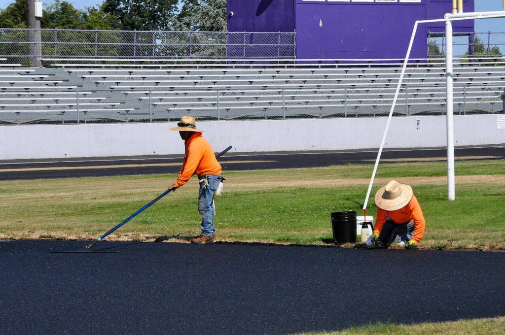Sequim Gazette photo by Matthew Nash
Workers with Beynon Sports of Oregon flatten new material for the high jump area on July 19.