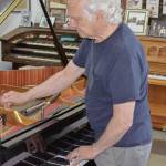 Sequim Gazette photo by Elijah Sussman / Paul Creech places a rubber mute between strings to prevent them from vibrating. June 22.