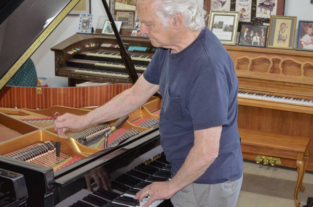 Sequim Gazette photo by Elijah Sussman / Paul Creech places a rubber mute between strings to prevent them from vibrating. June 22.