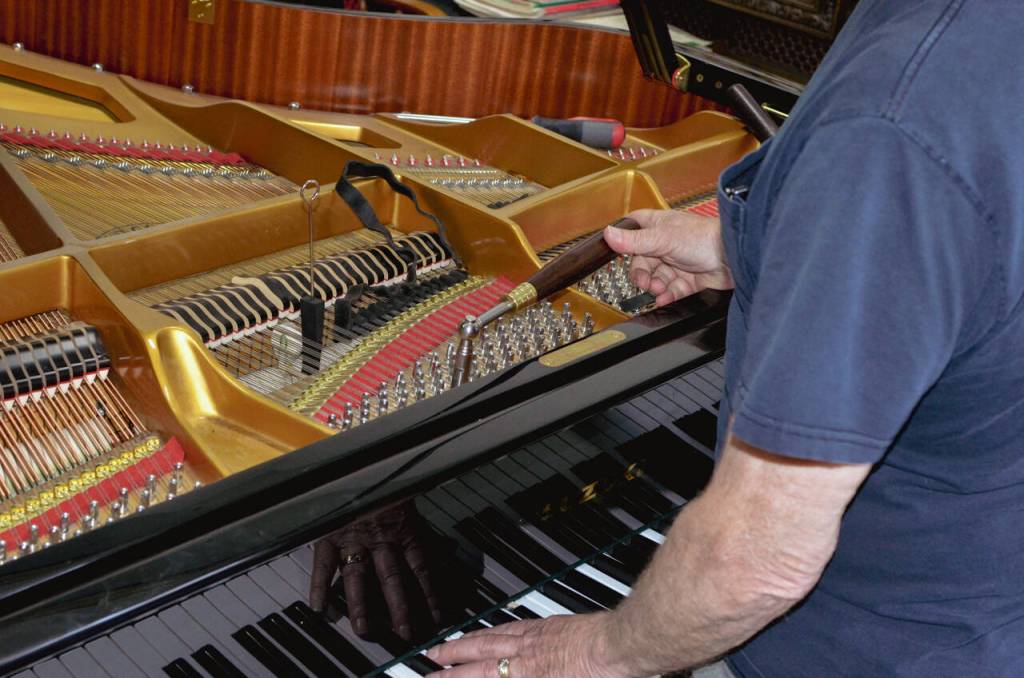 Sequim Gazette photo by Elijah Sussman / Paul Creech turns a tuning hammer on newly acquired grand piano.