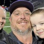 New Sequim athletic director/head football coach Ian Henley takes a family photo with his wife Jessica and son Rhys after a football game.
