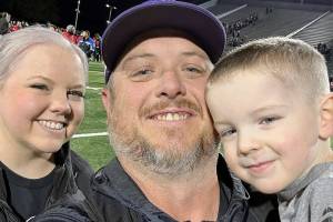 New Sequim athletic director/head football coach Ian Henley takes a family photo with his wife Jessica and son Rhys after a football game.