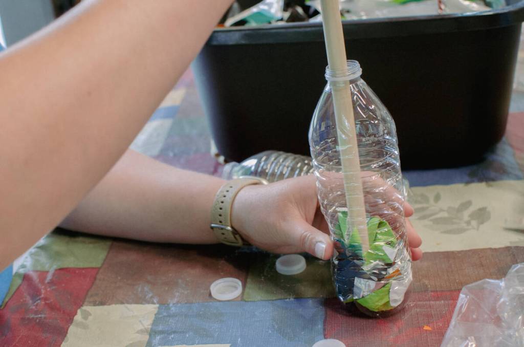 Sequim Gazette photo by Elijah Sussman / Eden Voebel demonstrates plastic compression for eco-brick on June 26.