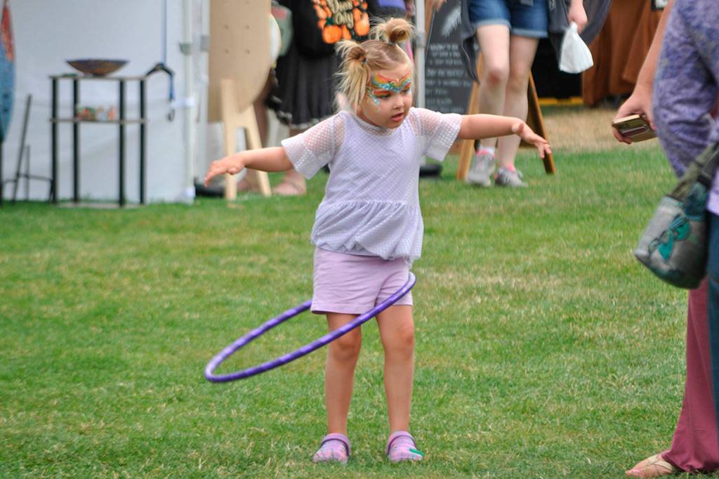 Sequim Gazette photo by Matthew Nash/ Lucy Willis, 3, of Bremerton tries out her hula hoop while walking with fresh face paint at the Sequim Lavender Festival in the Park on July 21.