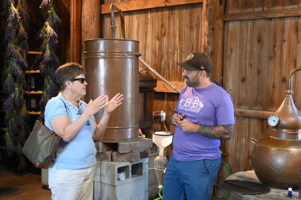 Sequim Gazette photo by Michael Dashiell / Carol Wheeler of Everett, talks with B&B Family Farm co-owner Zion Hilliker during the Lavender Weekend on July 20.