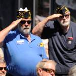 Christopher Bates and other veterans stand in salute as the Sequim City Band plays Armed Forces Salute at the unveiling of the Remember Me mural at the American Legion building.