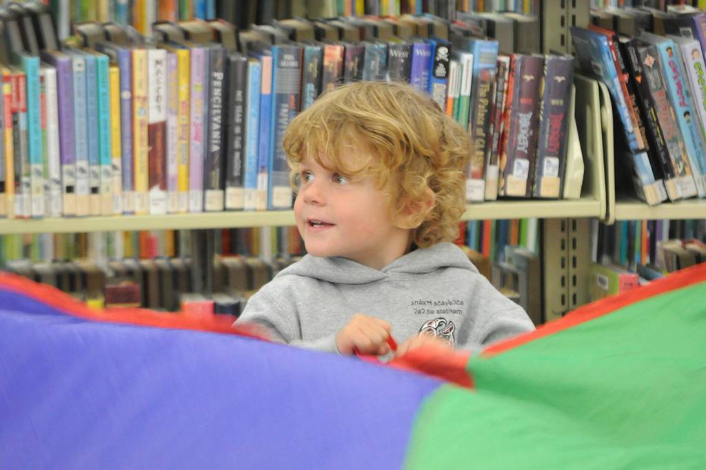 Two-year-old Rowan Grinnell enjoys playing with a parachute during Storytime with the Royalty on July 23 in the Sequim Temporary Library. His mom Martha said they try to come every week for Storytime.