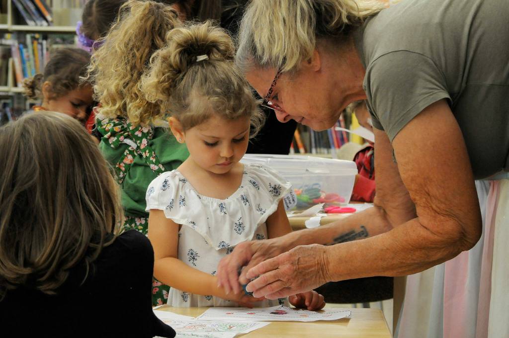 Sequim Gazette photo by Matthew Nash/ Sandi Shaw helps her granddaughter Sienna Shappie, 3, make a crown during the North Olympic Library Systems Storytime with the Royalty event. Shaw said she and granddaughters come all the time to the library.