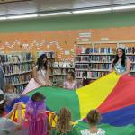 Sequim Gazette photo by Matthew Nash/ Sequim Irrigation Festival royalty and participants of Storytime with the Royalty enjoy playing with a parachute on July 23.