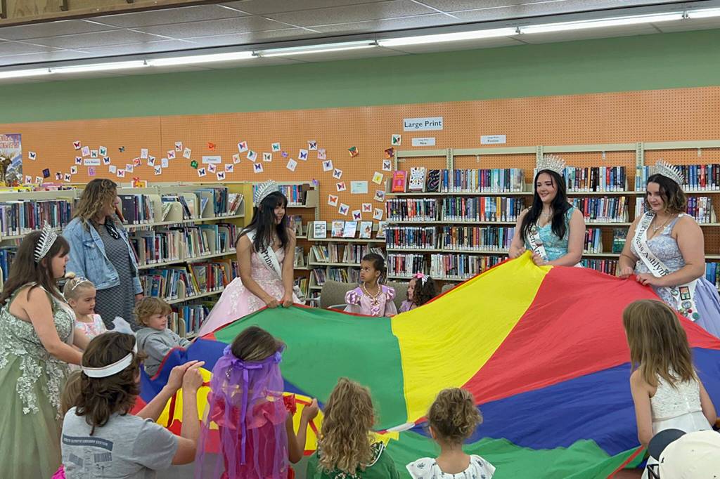 Sequim Gazette photo by Matthew Nash/ Sequim Irrigation Festival royalty and participants of Storytime with the Royalty enjoy playing with a parachute on July 23.