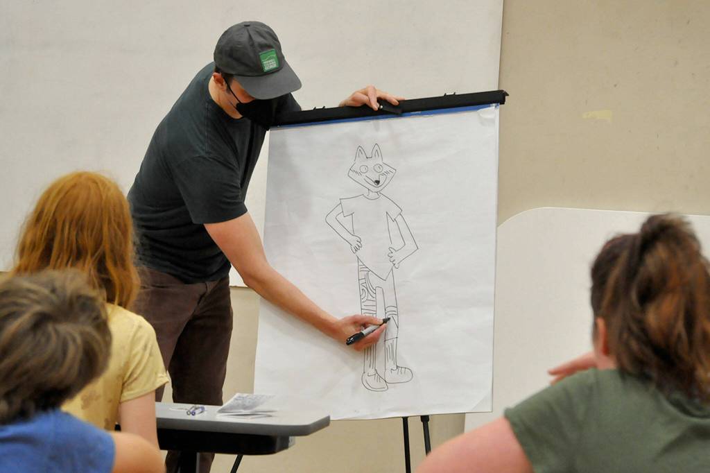 Sequim Gazette photo by Matthew Nash/ Cartoonist Aron Nels Steinke finishes a drawing of Sequims Cecily Erickson during a lesson on creating characters for childrens own comic books. Cecily requested he draw her as a red fox following the style of his Mr. Wolfs Class series.