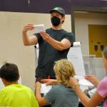 Sequim Gazette photo by Matthew Nash/ Cartoonist Aron Nels Steinke shows children how to fold a mini-comic during a lesson about making characters and comic books on July 31 in Sequim.