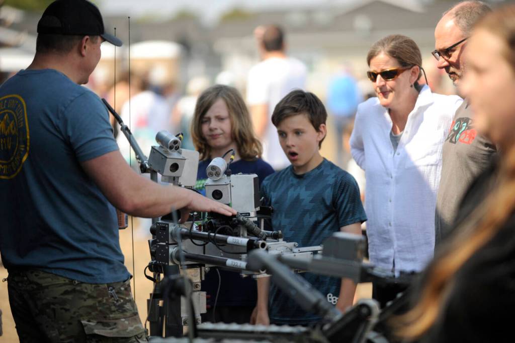 Sequim Gazette photo by Michael Dashiell / Miles Angelovic, 10, and Charlie Stewart, 11, both of Sequim learn about bomb disposing technology from Andre Gele, a U.S. Navy Explosive Ordnance Disposal bomb technician, at the Unity of Effort event in Aug. 10.