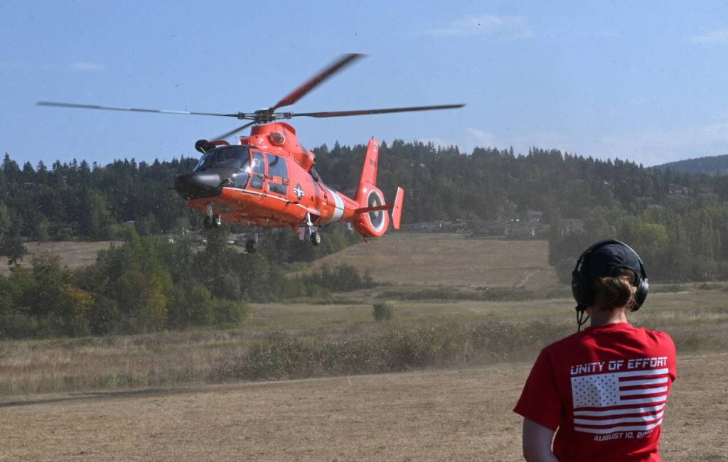 Sequim Gazette photo by Michael Dashiell / Madeline Patterson looks on as a U.S. Coast Guard helicopter leaves the Unity of Effort venue in Sequim on Aug. 10.