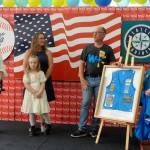 Sequim Gazette photo by Matthew Nash/ John-Paul and Jessica Davis, right, present a shadowbox of Lynie Staus work vest to his wife Donna and granddaughter Jordyn on Aug. 2 during a ceremony for the Sequim Walmarts remodel. Staus worked for Sequim Walmart since it opened.