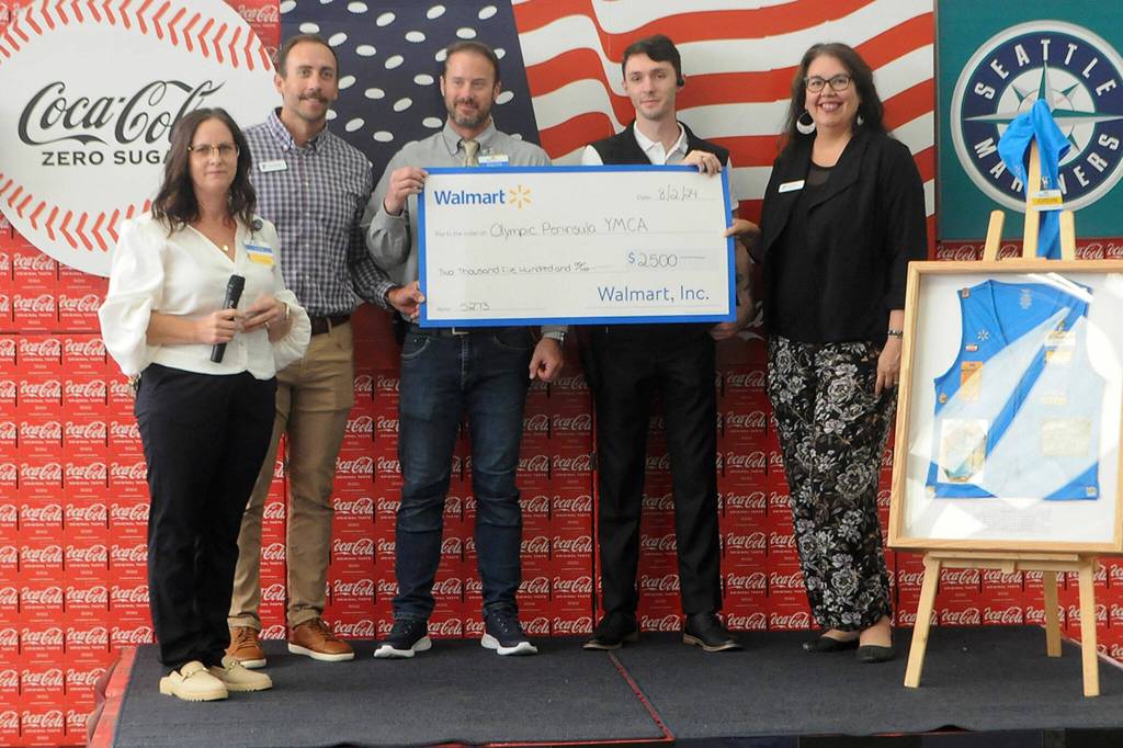 Sequim Gazette photo by Matthew Nash/ YMCA of the Olympic Peninsula staffers accept a $2,500 donation from Sequim Walmart staff on Aug. 2.