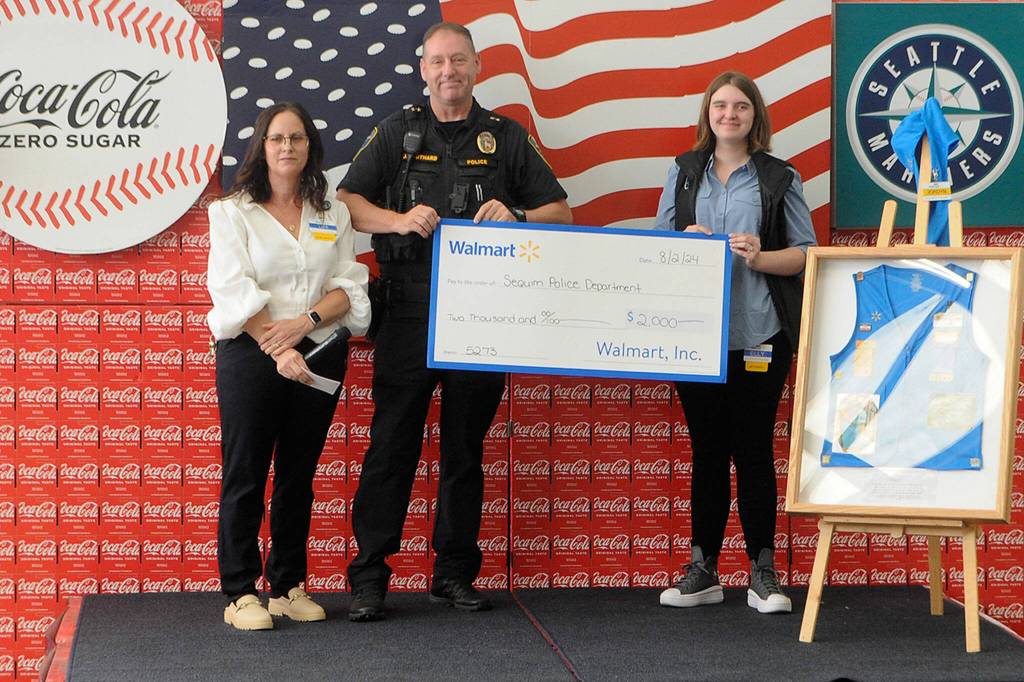 Sequim Gazette photo by Matthew Nash/ Deputy Police Chief John Southard accepts a $2,000 donation for the department from Sequim Walmart staff on Aug. 2.