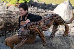 Photo courtesy of Molly Omann / Driftwood artist Molly Omann, poses with her life-sized cougar sculpture, which will be on display at Sequim Museum & Arts in April and during the First Friday Art Walk.