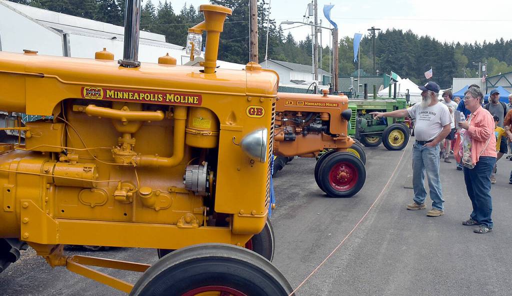 Photo by Keith Thorpe/Olympic Peninsula News Group / Ron Rottler and Tammi Moses, both of Port Angeles, examine a line of tractors on display at the Clallam County Fair on Aug. 17.