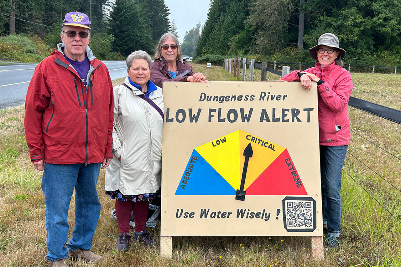 Sequim Gazette photo by Matthew Nash
David Brehm, Jeene Hobbs, Barbara VanderWerf and Ann Soule with the Clallam County League of Women Voters stand with a new sign that shows the level of water flow for the Dungeness River. While the river flow was considered critical on Aug. 23, that night, levels improved slightly to low flow. Soule said, the Critical zone was set for when irrigation managers potentially have to cut back their diversions and when biologists start planning ways to facilitate migration of salmon through shallow channels. The sign is just west of Knutsen Farm Road on Old Olympic Highway. The group worked in conjunction with Tony Corrado, Mary Foster, Carrol Hull and Bonnie Bless-Boenish on information for the sign and website, with a QR code for up-to-date information. The sign will be updated weekly, organizers said.