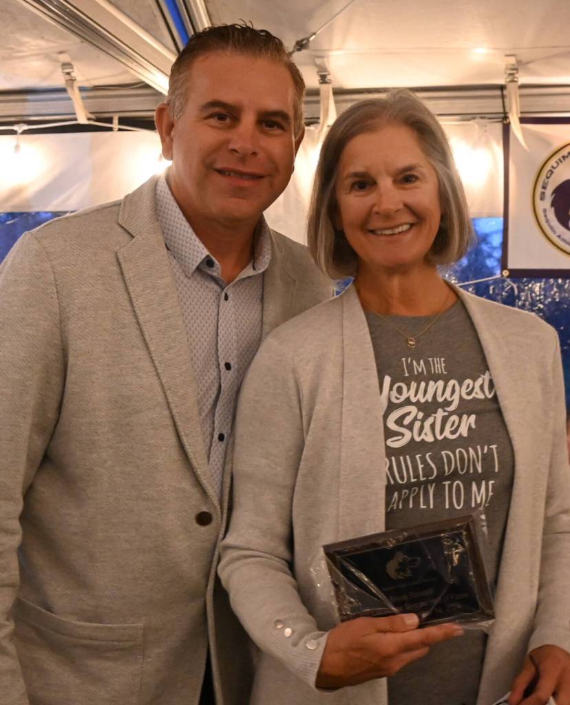 Sequim Gazette photo by Michael Dashiell / Jan Randall Crollard accepts the 2014 Sequim Athletic Hall of Fame plaque for her father Bruce Randall, from Hall president Derrin Doty, at the event, held at The Cedars at Dungeness golf course on Sept. 14.