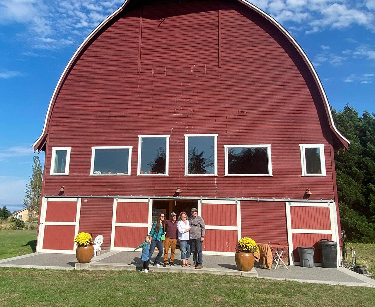 Photos courtesy Mary Beth Holladay
Family members, from left, five-year-old Ronin, Lindsay Holladay Van Damme, Chris Van Damme, and Mary Beth and Rick Holladay stand outside their barn  the Dungeness landmark Cline-Bigelow Barn  to celebrate its 90th birthday with family and friends.