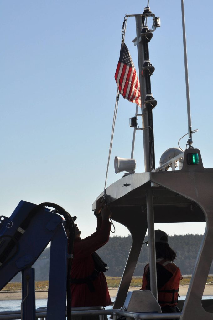 Sequim Gazette photo by Matthew Nash/ Dr. John Vavrinec, research scientist/dive officer at PNNL-Sequim, raises the flag for the RV Resilience dedication on Sept. 5.