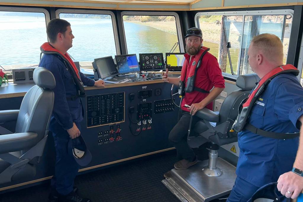 Sequim Gazette photo by Matthew Nash/ Jakob Bueche, captain of the RV Resilience, center, speaks with Lt. Anthony Pinto, left, and Lt. Cmdr. John Robertson out of Seattle about the specifics of the new hybrid vessel that can carry up to 5,000 pounds in research equipment while alternating between diesel and electric engines.