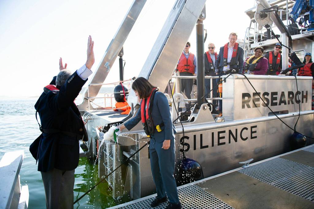Photo courtesy Andrea Starr/ Pacific Northwest National Laboratory/ Senator Maria Cantwell breaks a bottle of nonalcoholic cider over the RV Resilience on Sept. 5 as Steve Ashby, PNNL laboratory director, and other dignitaries celebrate the dedication of the new hybrid vessel.