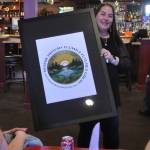 Sequim Gazette photo by Matthew Nash
Michelle Rhodes, executive director of the Sequim Irrigation Festival, shows festival royalty the new logo and tagline Where History Flows and Futures Grow for the 130th festival on Oct. 12 at the Oasis Bar and Grill. Sherry Scharschmidt designed the logo for the second year.