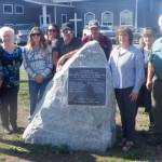 Photo courtesy of Rhodefer family 
Rhodefer family members (from left) Joan Morrish, Patty Brueckner, Bailey Rhodefer, Kenzi Rhodefer, Dean Rhodefer, Jay Rhodefer, Anita Reynods and Keri Rhodefer join pastor Jerry Luengen at a monument in Carlsborg honoring locals who lost their lives fighting World War I. The Rhodefer family recently restored the marker.