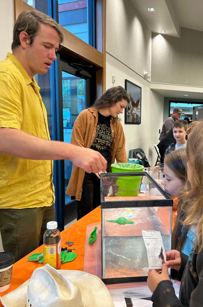 Sequim Gazette photo by Matthew Nash/ Chris Rumple, a mechanical engineer, and Cailene Gunn, an earth scientist for Pacific Northwest National Laboratory, speak with students at the Dungeness River Festival about how researchers look to use waves in the ocean to generate energy through buoys.