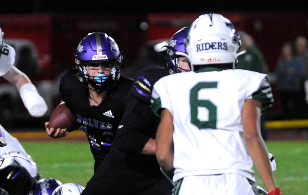 Sequim Gazette photo by Michael Dashiell / Sequim quarterback Zeke Schmadeke, left, looks to get past Port Angeles Tucker Swain in the Wolves 27-7 Rainshadow Rumble win over the Roughriders on Sept. 27. Schmadeke had 150 yards rushing and two scores in the win.