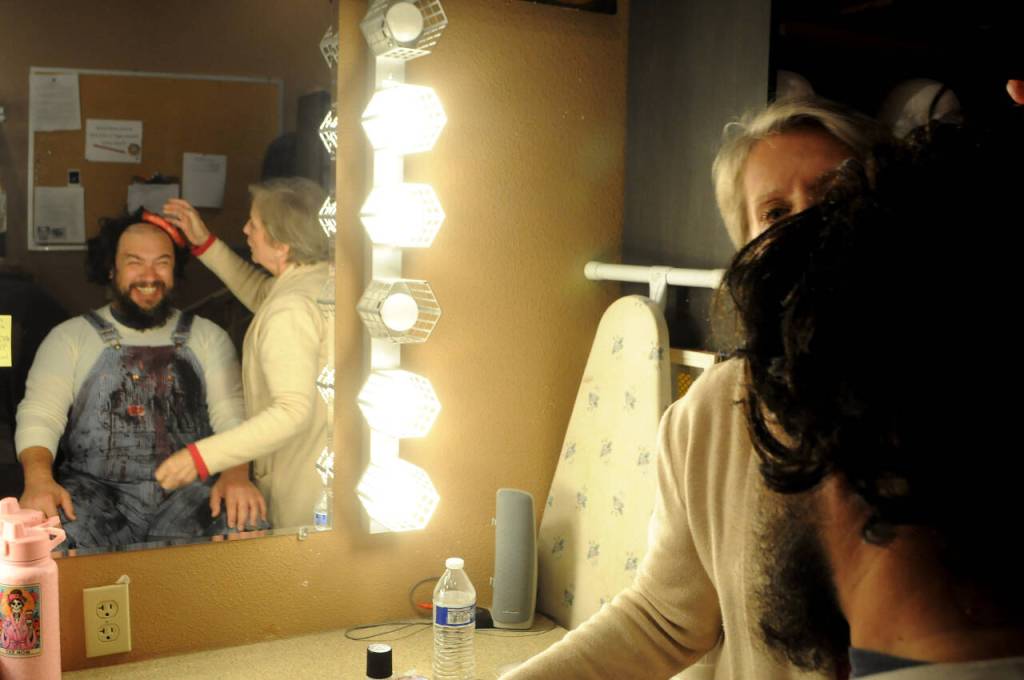 Sequim Gazette photo by Matthew Nash/ Christopher Woods, a first time actor at Olympic Theatre Arts, smiles as Cheri Martin places a wig to complete his zombie look for Night of the Living Dead. Shows run in Sequim Oct. 18-27.