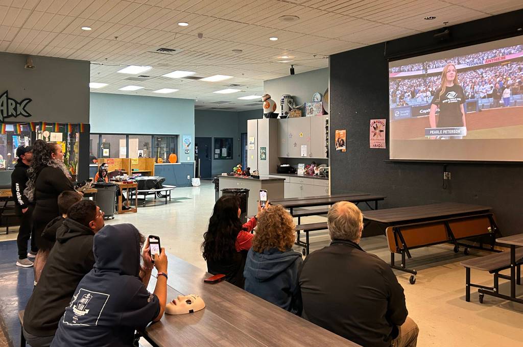 Sequim Gazette photo by Matthew Nash/ Staff, board members, and club members with the Boys & Girls Clubs of the Olympic Peninsula watch from the Sequim club Pearle Peterson, a former club member and staffer, sing the national anthem at the World Series in Los Angeles on Oct. 26.