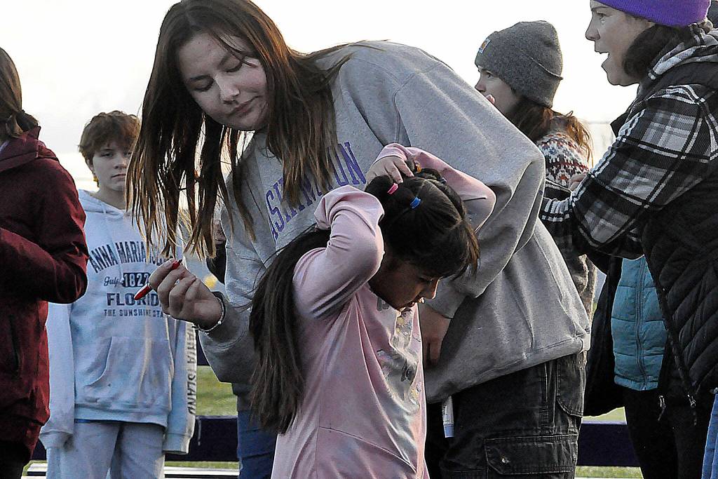 Sequim Gazette photo by Matthew Nash/ Sequim High School junior Melia Nelson helps third grader Alice Salgado record how many laps shes run during the Turkey Trot.