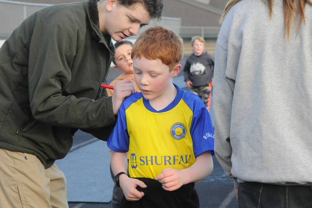 Sequim Gazette photo by Matthew Nash/ Sophomore Trenton Downs marks another lap for second grader Jaxson Schroeder at the Sequim Elementary PTA Turkey Trot.