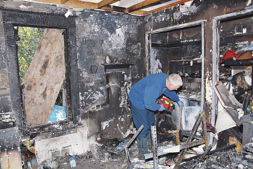 Firefighter Kevin Van De Wege inspects a burned dryer inside a fire-ravaged room at a residence on Jamestown Road in Sequim in 2011. Van De Wege, who served in political office while also a firefighter, was promoted to captain in 2021, and will continue to serve Clallam County Fire District 3 for a few more years until retiring, he said.