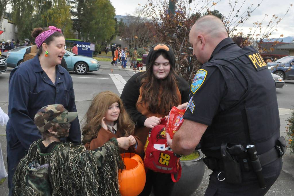 Sequim Gazette photo by Matthew Nash/ Sgt. Dave Campbell with Sequim Police Department hands out candy to Aliya Smith and cousins on Halloween at Centennial Place.