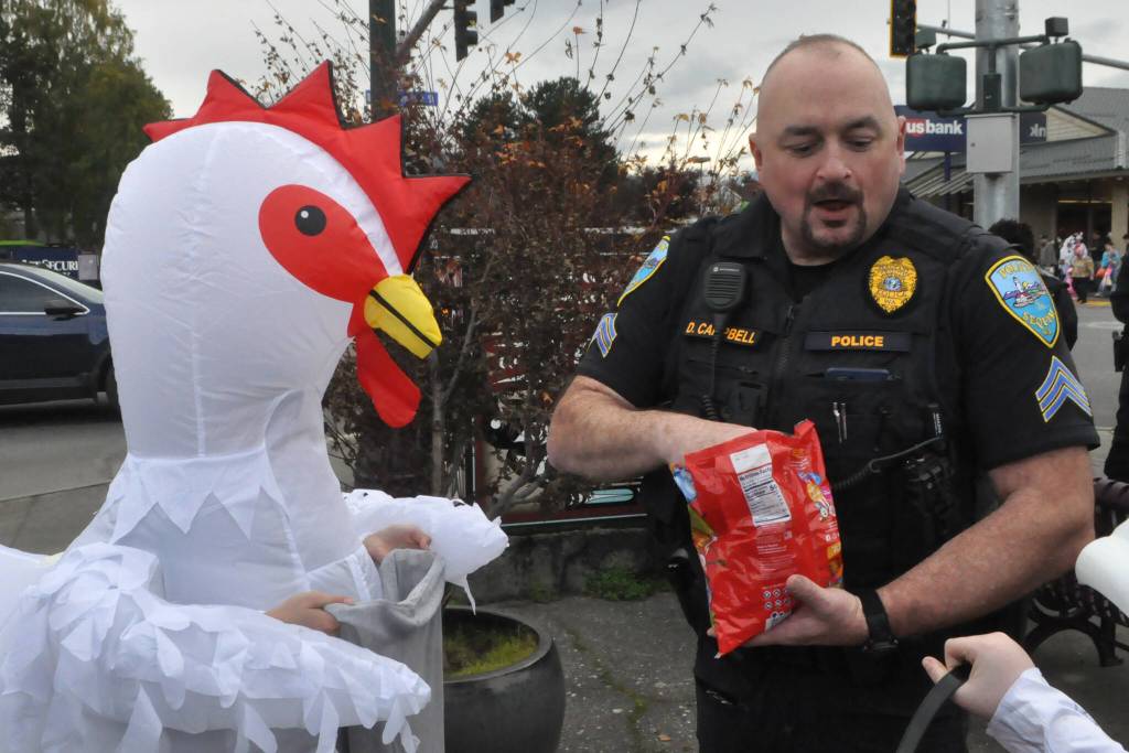 Sgt. Dave Campbell with Sequim Police Department hands out candy to trick-or-treaters on Halloween from Centennial Place at the corner of Washington Street and Sequim Avenue.