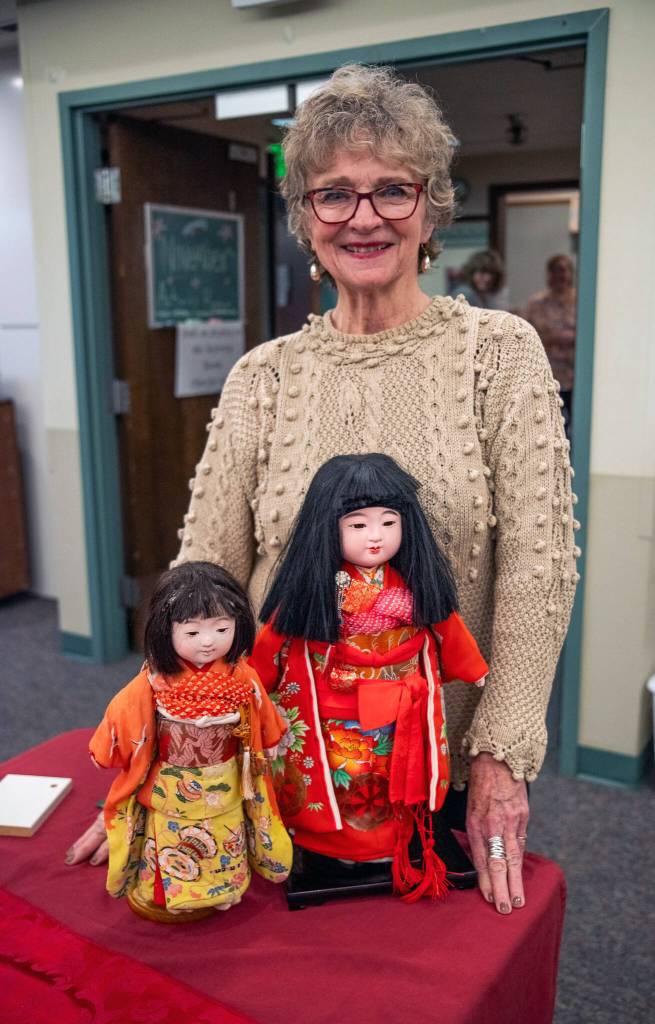 Sequim Gazette photo by Emily Matthiessen/ Olympic Peninsula Doll Club member Connie Schulz stands with two fully apparelled dolls, part of her Japanese doll collection which she shared with this public last Saturday at Sherwood Assisted Living. Schulz was a set-designer for Disney stationed in Tokyo when she began her collection.