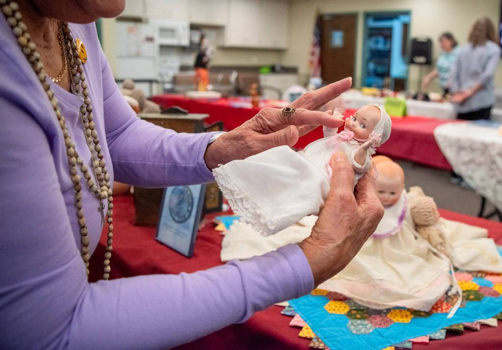 Sequim Gazette photo by Emily Matthiessen/ During the Olympic Peninsula Doll Clubs Timeless Treasures, a resident of Sherwood Assisted Living (which hosted the event) admires an antique baby doll. She was one of many residents and visitors enjoying the trip into the past.