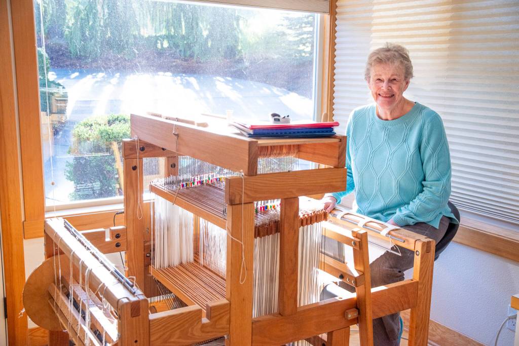 Sequim Gazette photo by Emily Matthiessen/ Lynn Baritelle, one of the North Olympic Shuttle and Spindle Guilds 88 members, sits at the computerized loom which is capable of weaving 16-18 shaft patterns.