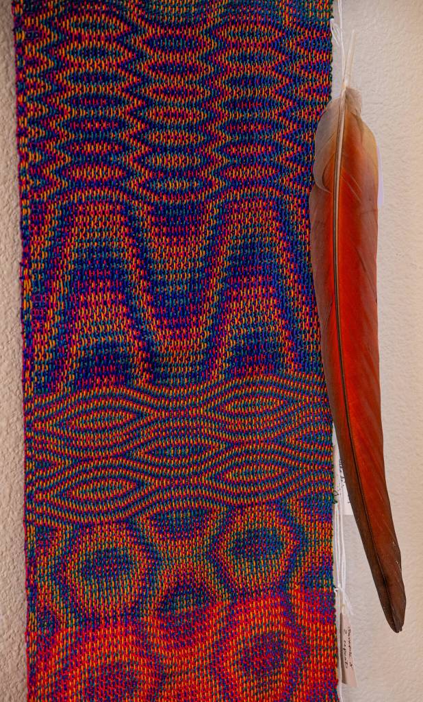 Sequim Gazette photo by Emily Matthiessen/ Master weaver and Sequim resident Lynn Baritelle wove this cloth to match the colors in the irridescent feather to the right.