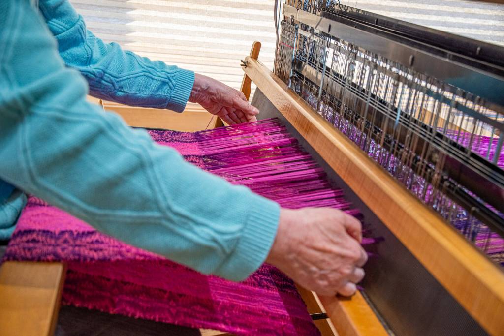 Sequim Gazette photo by Emily Matthiessen/ Lynn Baritelle, master weaver, demonstrates the weaving of cloth on her loom in her home workshop.