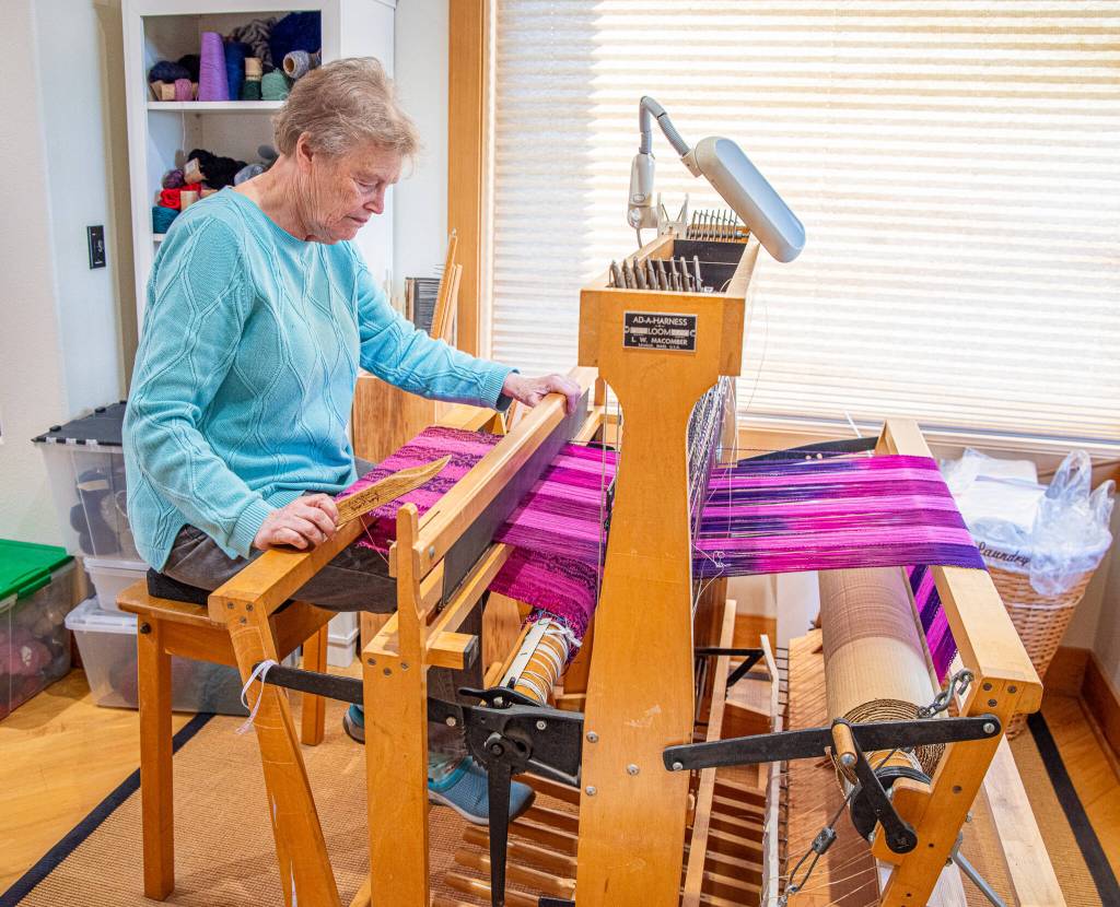 Sequim Gazette photo by Emily Matthiessen/ Lynn Baritelle, master weaver, demonstrates the weaving of cloth on her loom in her home workshop.